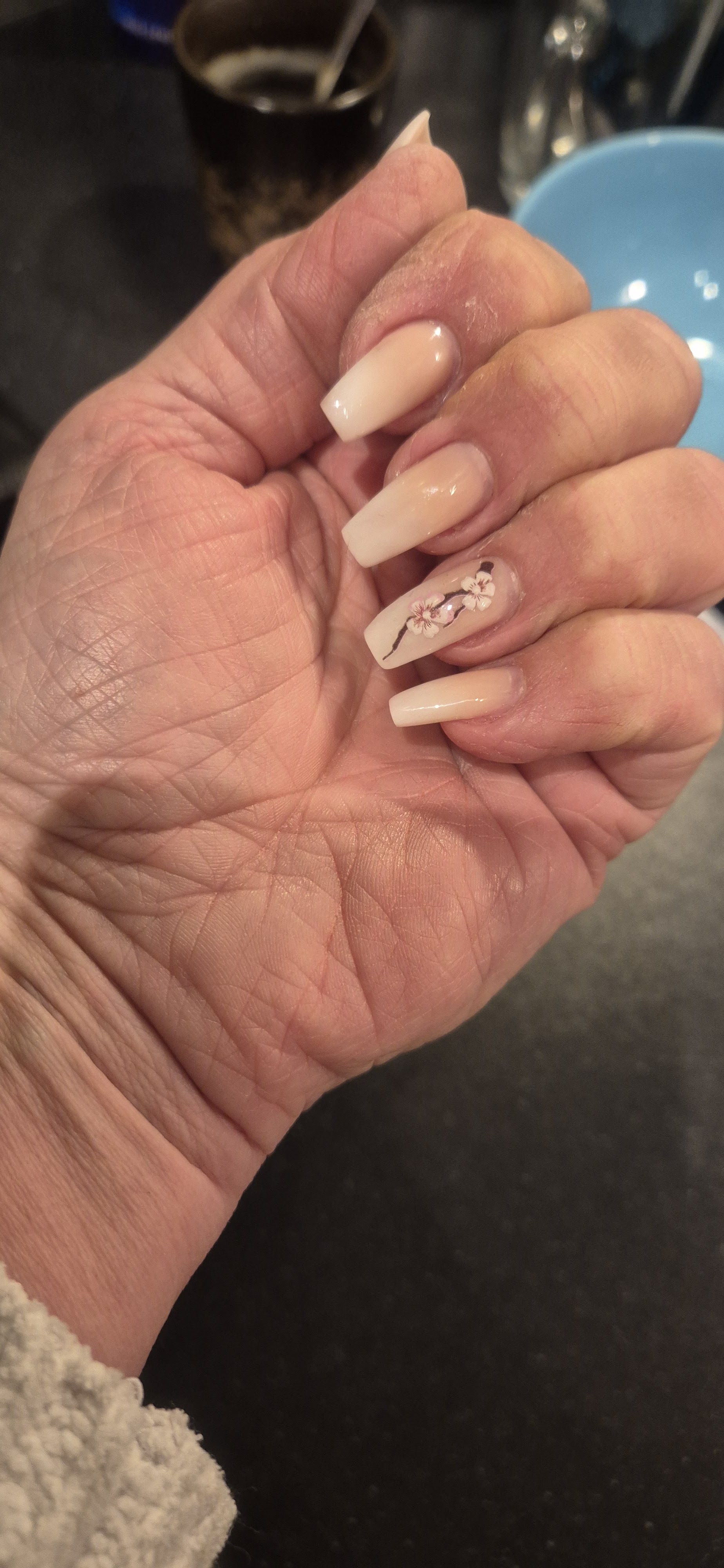 Hand van een klant met lange nude ombré nagels