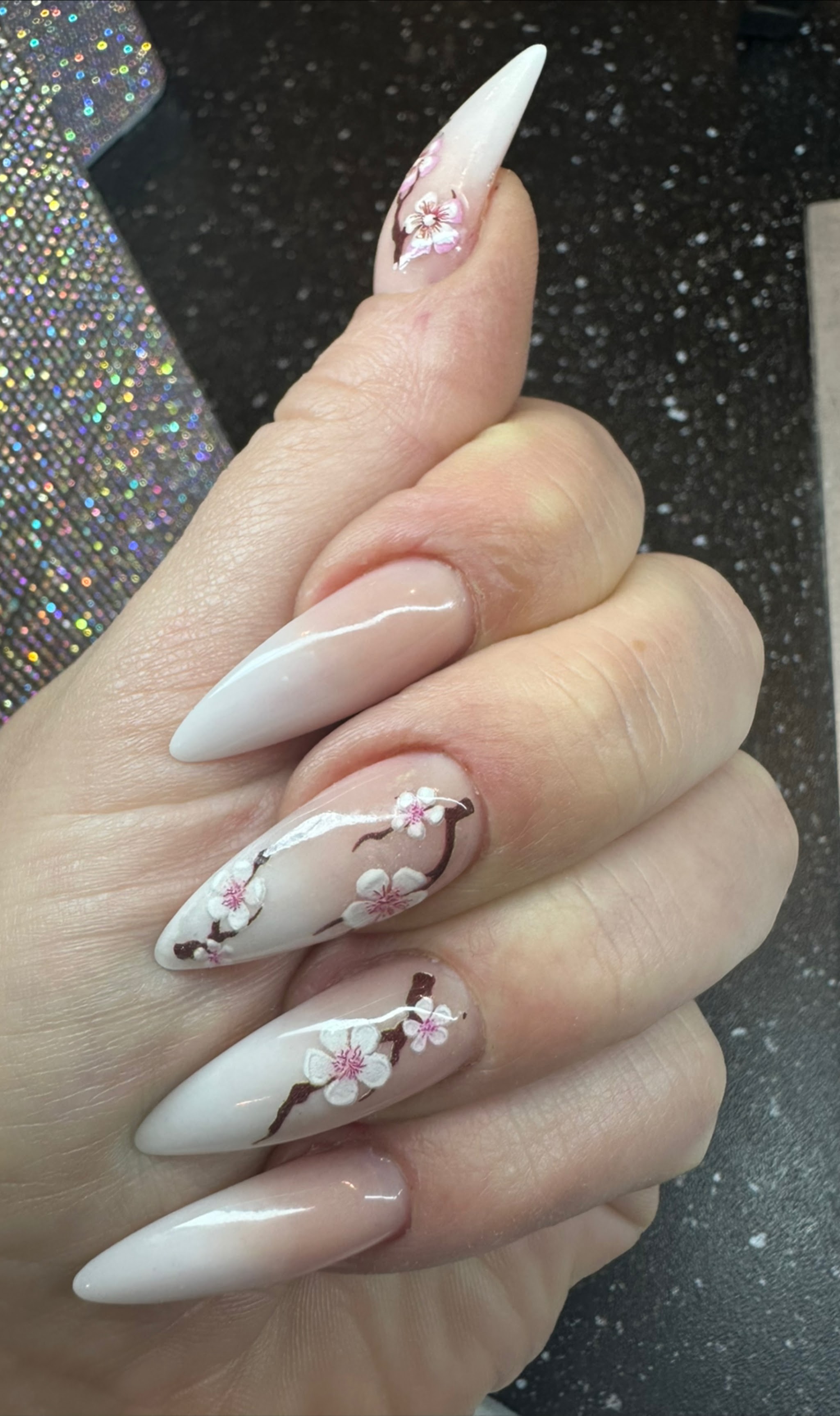 Lange witte stiletto nagels met roze kersenbloesem nailart